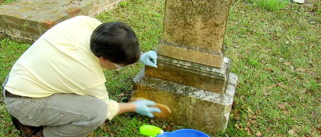 Photo of a man cleaning a headstone